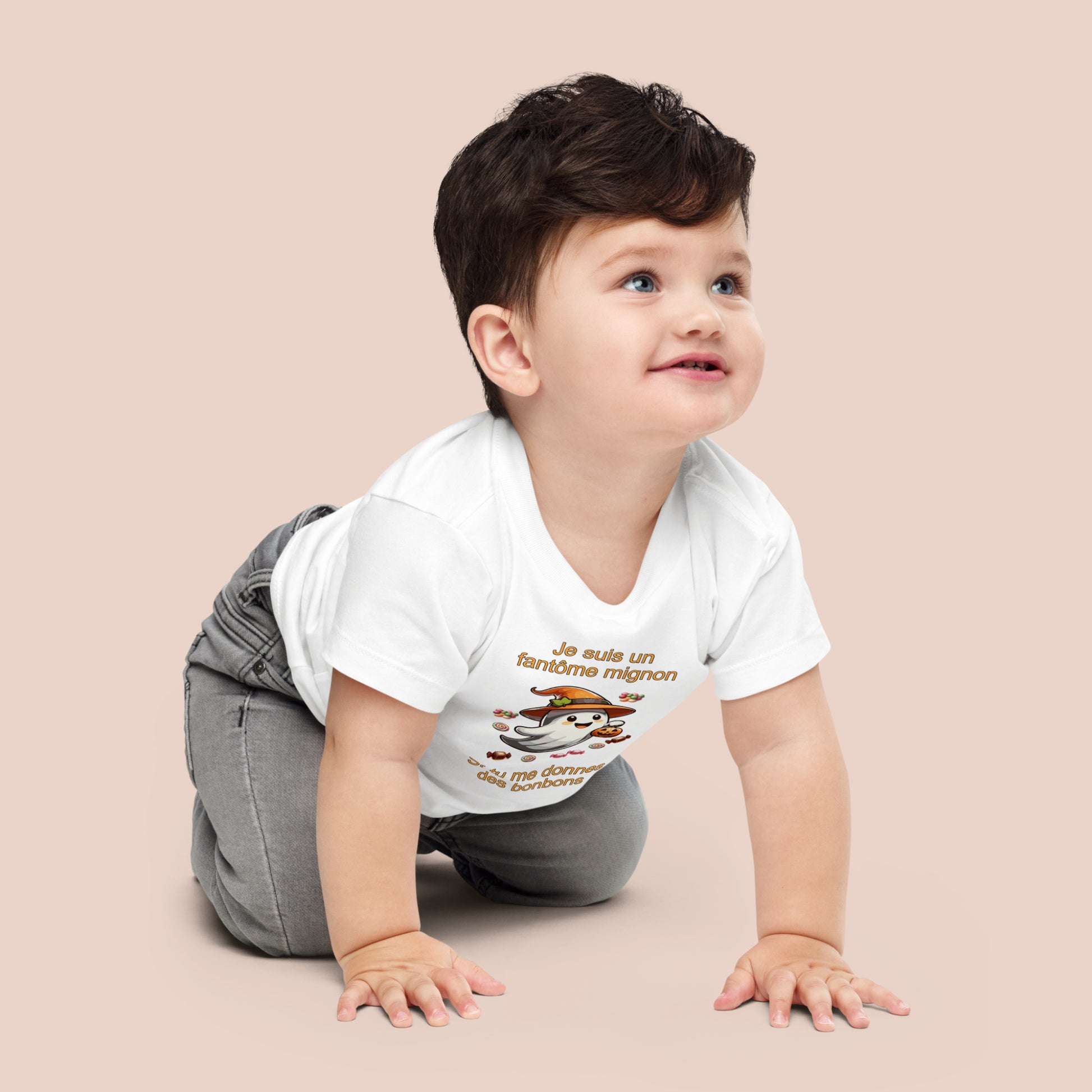 bébé à quatre pattes portant un t-shirt d'Halloween blanc imprimé d'un mignon fantôme entouré de bonbons et inscrit Je suis un fantôme mignon si tu me donnes des bonbons. Vue du devant.
