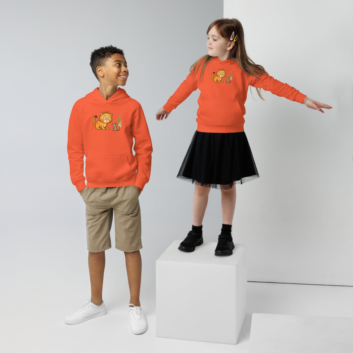 Deux enfants portant un hoodie orange imprimé d'un jeune chat surpris voyant une souris. Vue du devant