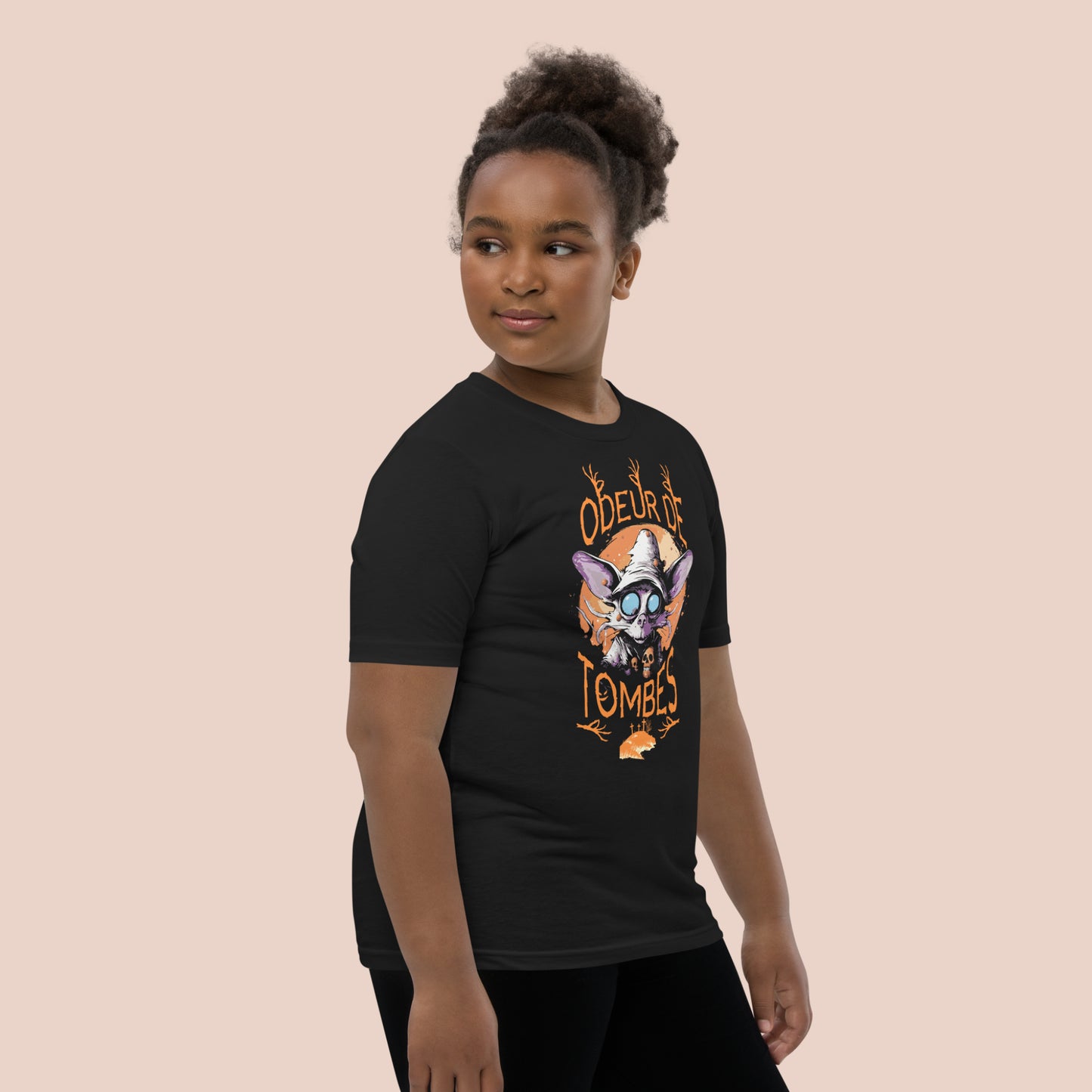 Fillet souriante portant un t-shirt d'Halloween noir avec illustration d'un monstre et inscription Odeur de tombes. Vue du côté droit.