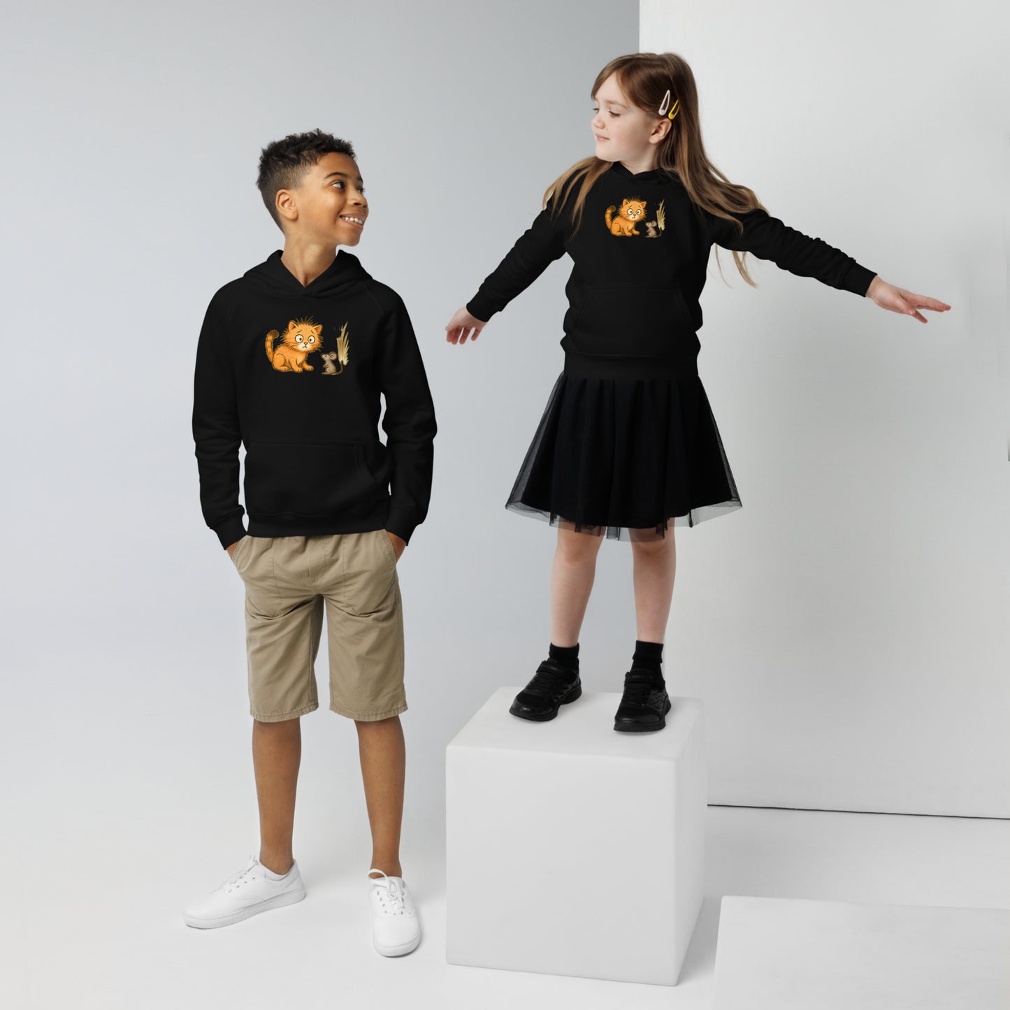 Deux enfants s'amusant portant un hoodie noir imprimé d'un chat surpris voyant une souris. Vue du devant