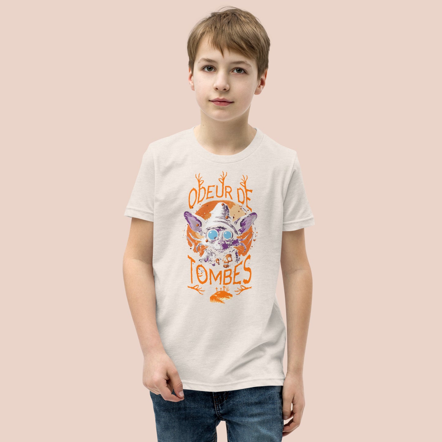 Garçcon sérieux portant un t-shirt de couleur naturel illustré d'un monstre et inscrit Odeur de tombes. Vue du devant.