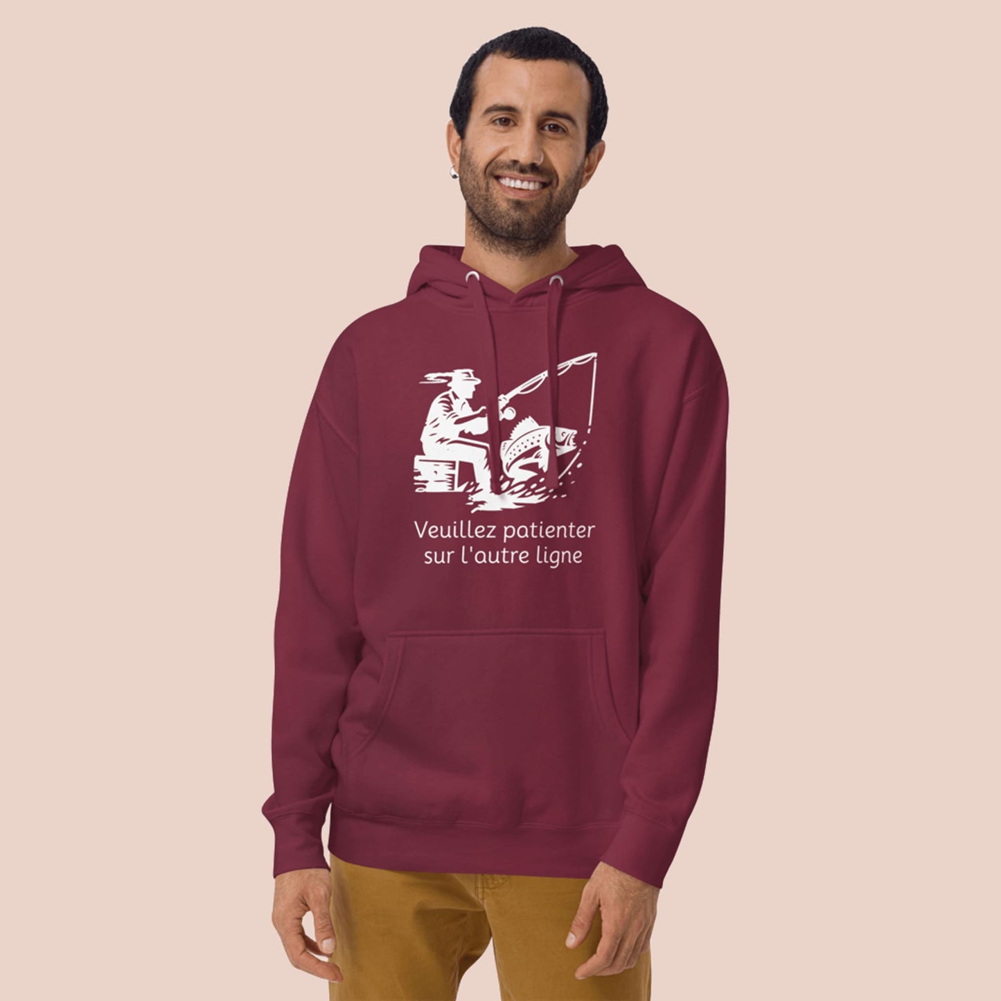 Homme portant un hoodie bordeaux avec motif pêcheur et texte « Veuillez patienter sur l'autre ligne » - Artic60
