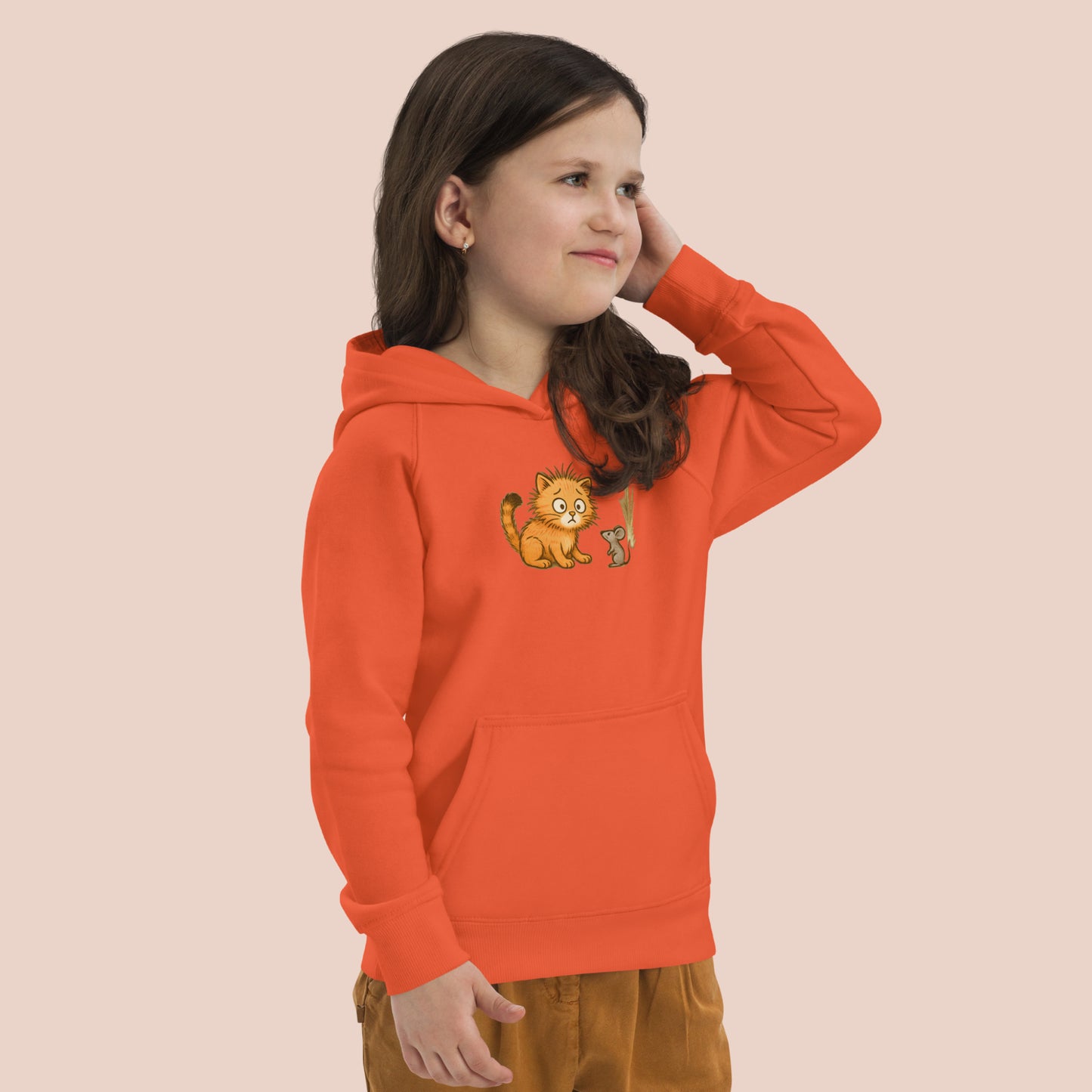 Fillette souriante portant un hoodie orange imprimé d'un jeune chat surpris voyant une souris. Vue du côté droit
