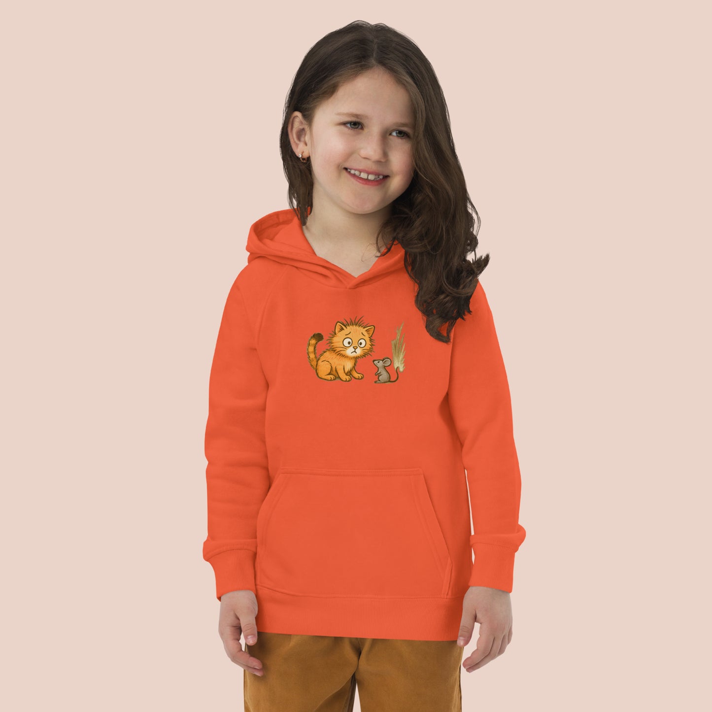 Fillette souriante portant un hoodie orange imprimé d'un jeune chat surpris voyant une souris. Vue du devant