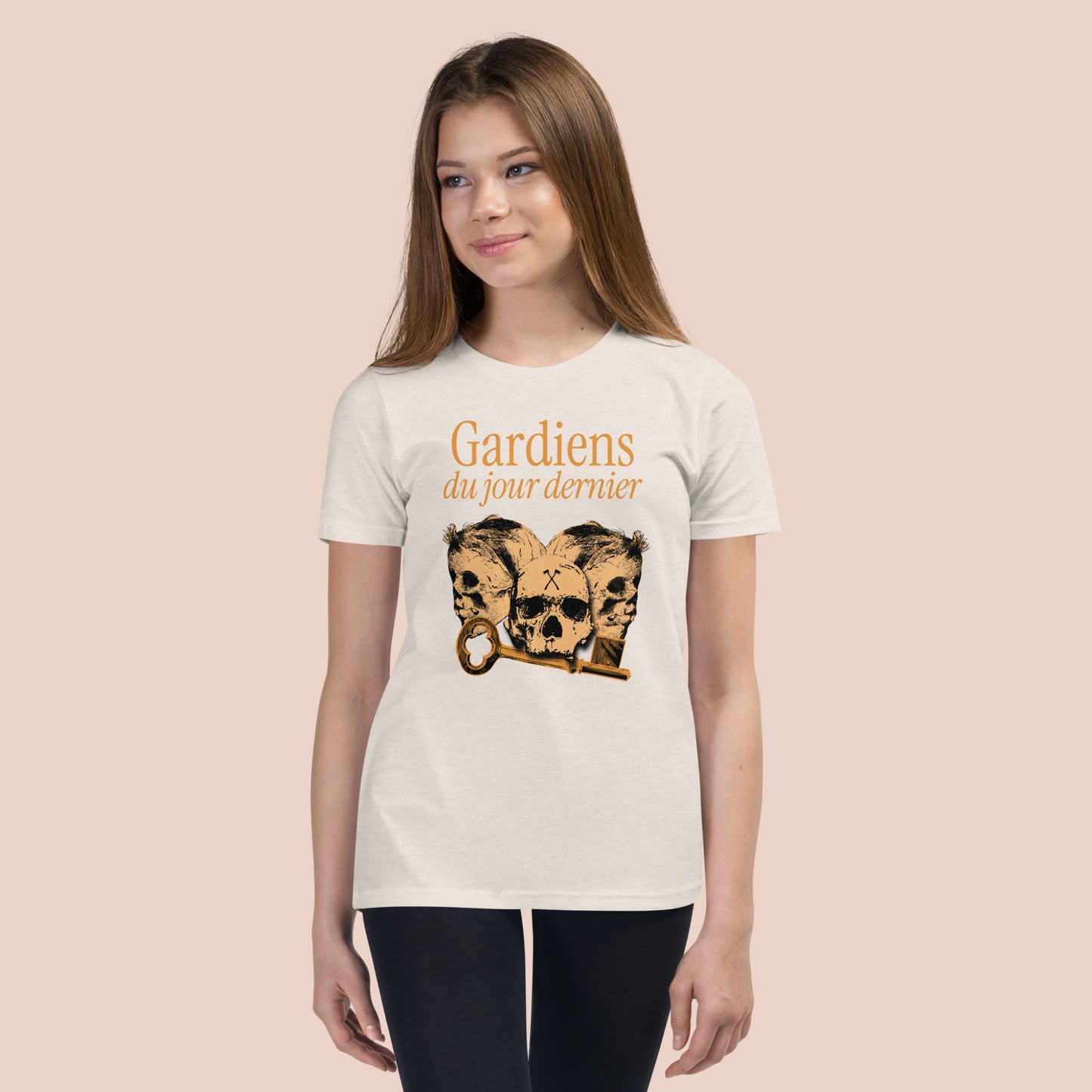 Fille souriante portant un t-shirt de couleur naturel illustré de têtes de squelette et inscrit Gardiens du jour dernier. Vue du devant.
