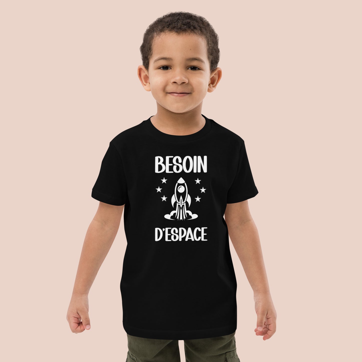 Garçon souriant portant un T-shirt noir fait de conton biologique. Texte imprimé : Besoin d'espace. Vue du devant