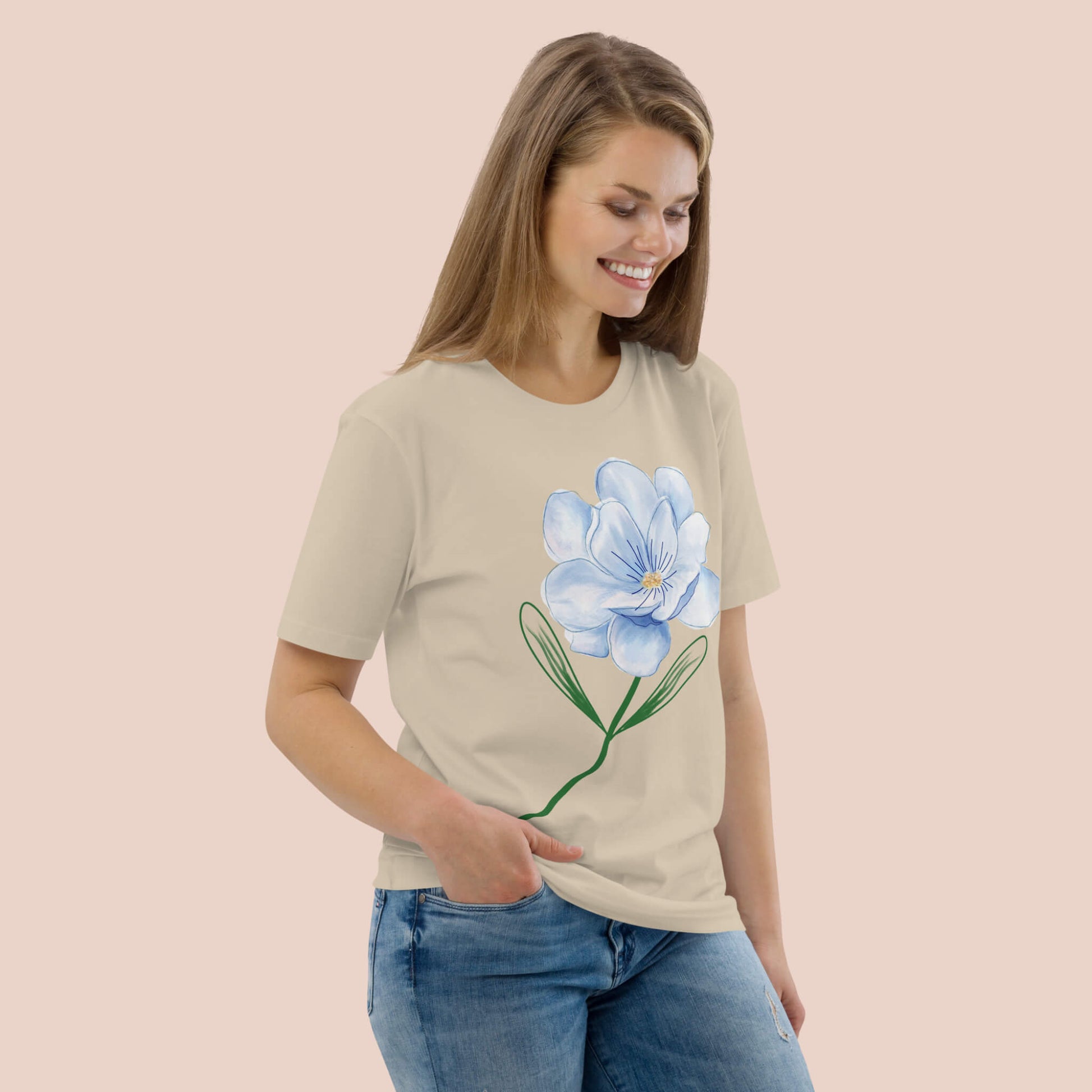 Femme souriante portant un t-shirt beige en coton bio avec une fleur bleue peinte – Artic60