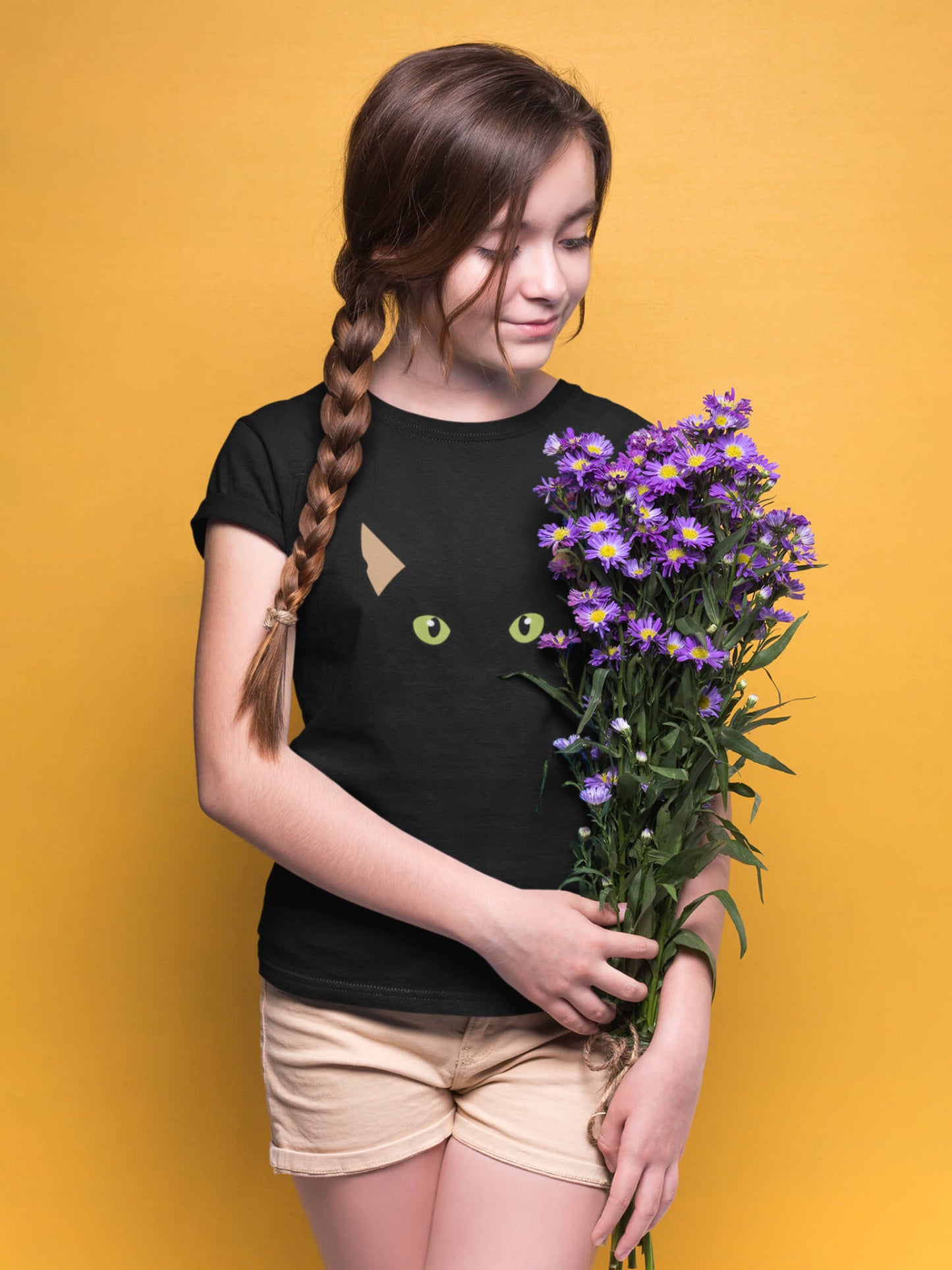 Fille en t-shirt noir avec un design de chat discret, tenant un bouquet de fleurs violettes – Artic60