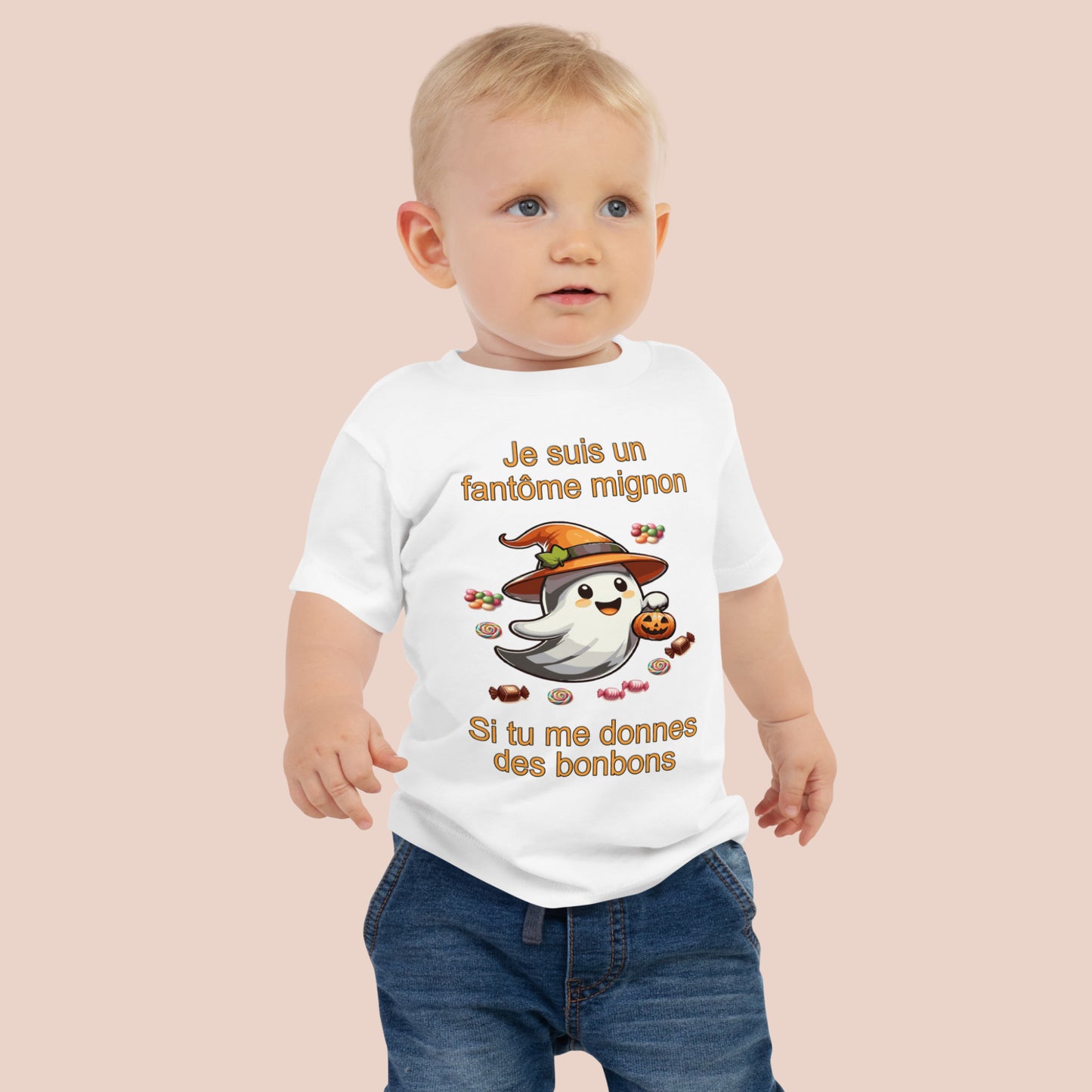 bébé portant un t-shirt d'Halloween blanc imprimé d'un mignon fantôme entouré de bonbons et inscrit Je suis un fantôme mignon si tu me donnes des bonbons. Vue du devant.