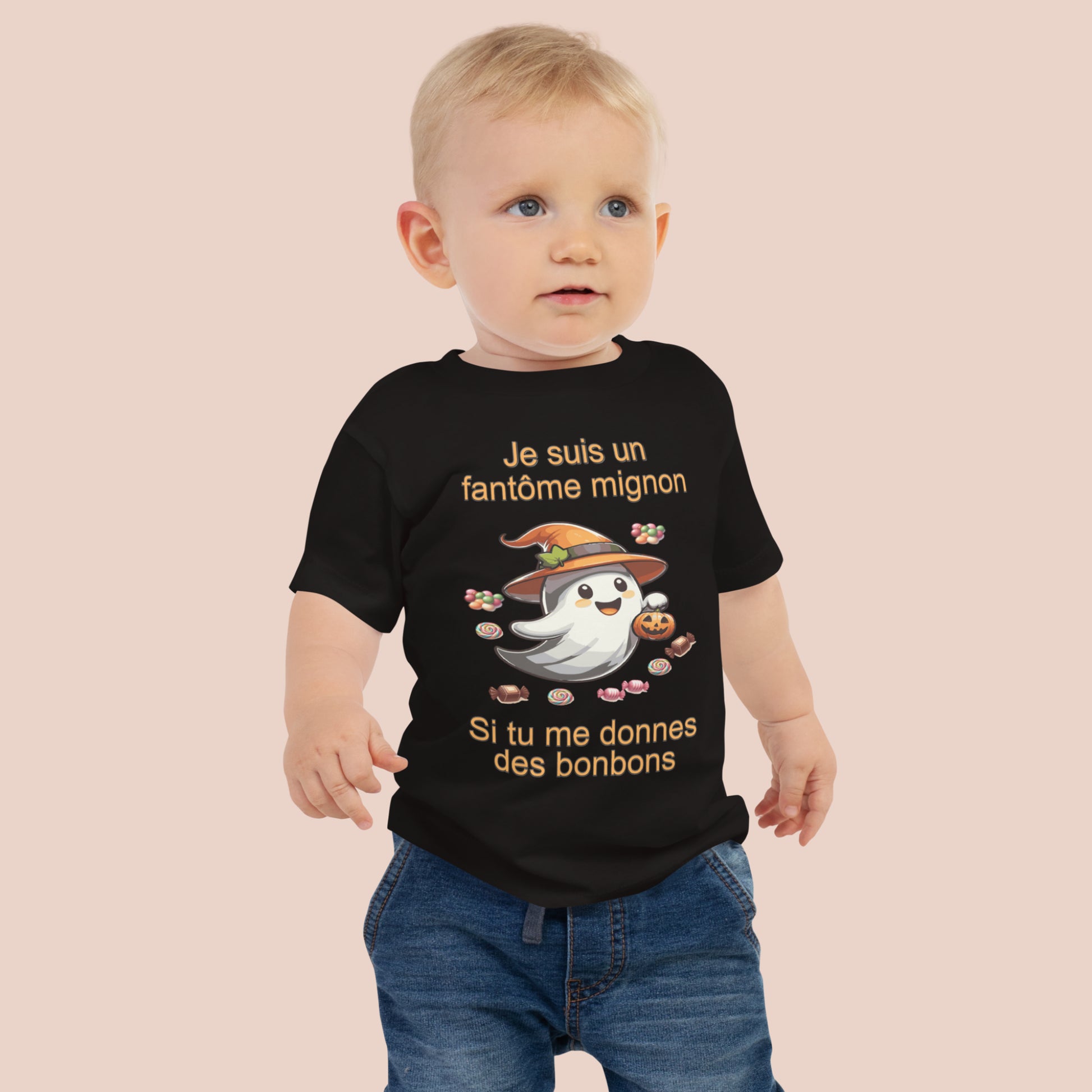 bébé portant un t-shirt d'Halloween noir imprimé d'un mignon fantôme entouré de bonbons et inscrit Je suis un fantôme mignon si tu me donnes des bonbons. Vue du devant.