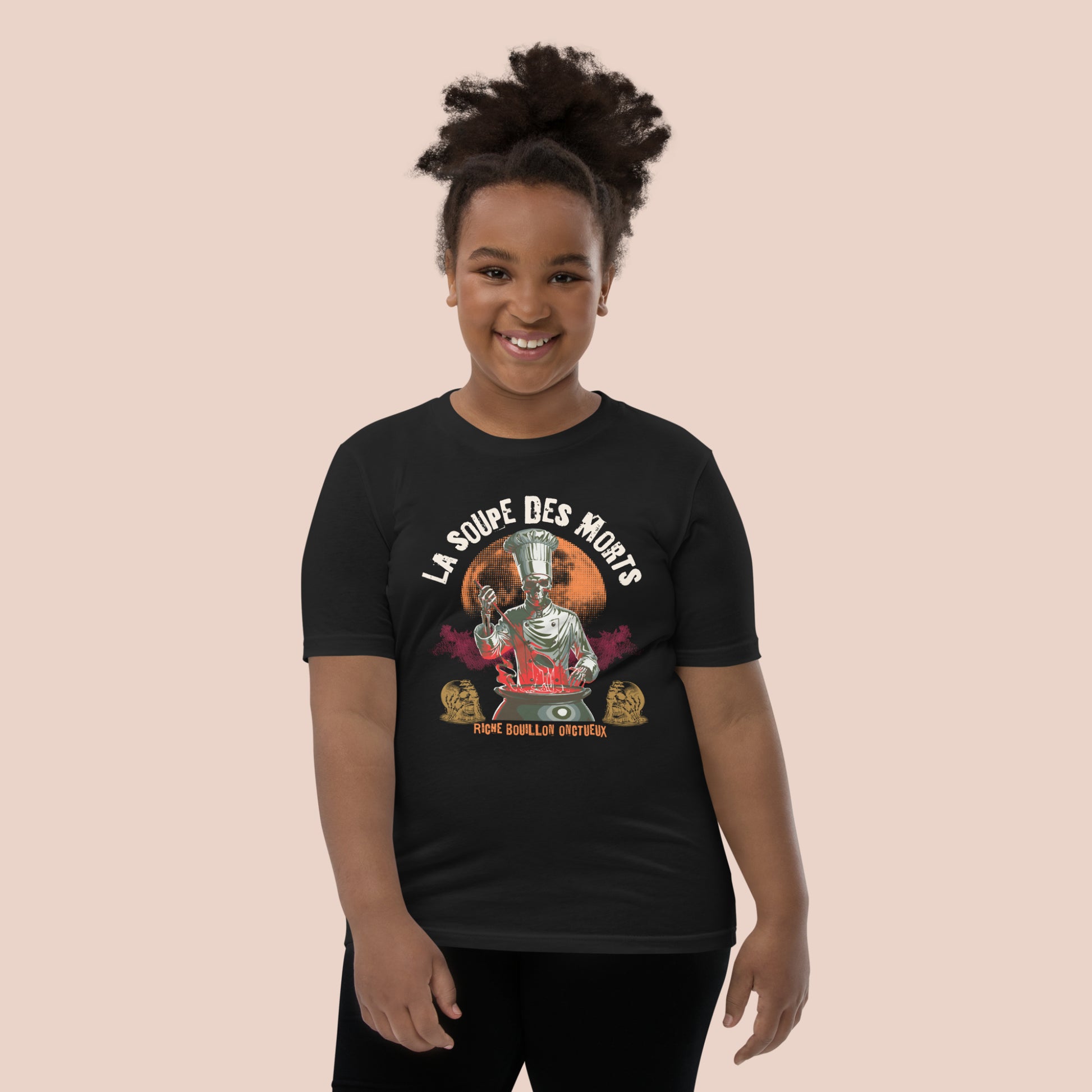 Fillet joyeuse portant un t-shirt d'Halloween noir avec illustration d'un chef monstre et inscription La soupe des morts. Vue du devant.