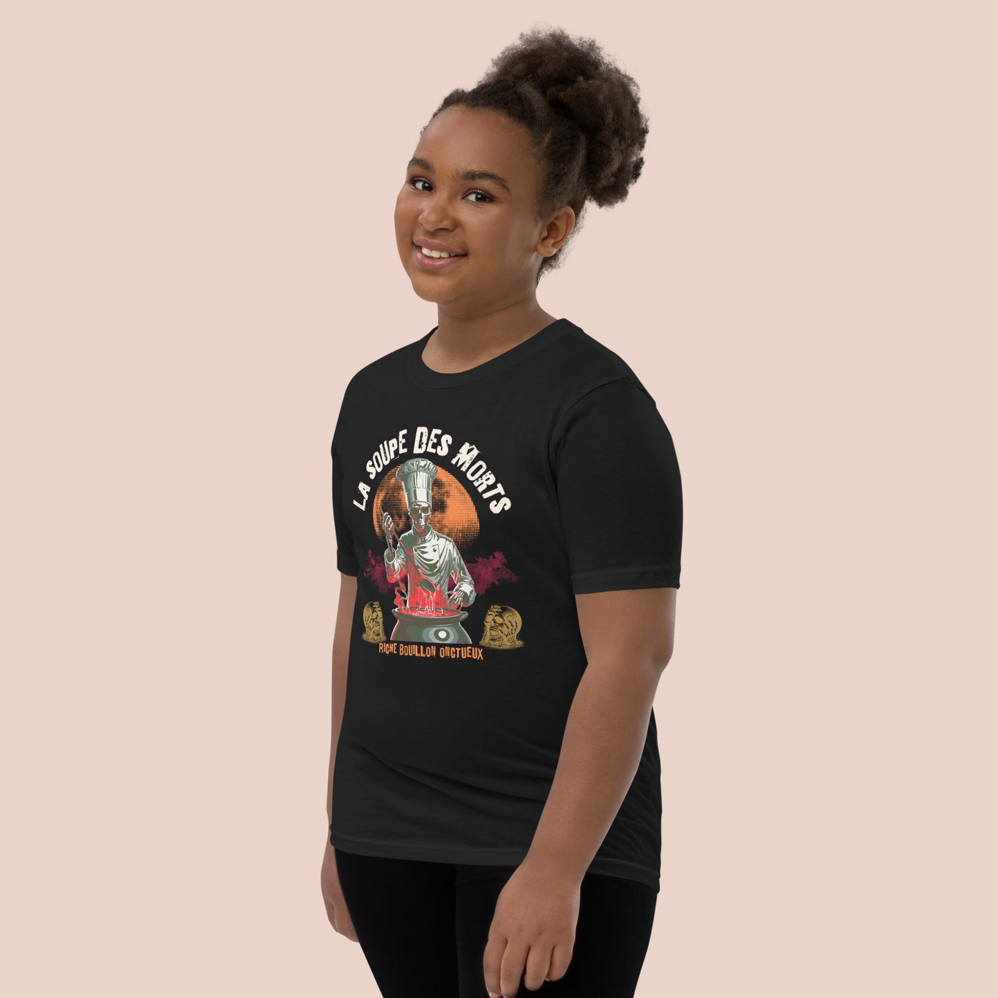 Fillet souriante portant un t-shirt d'Halloween noir avec illustration d'un chef monstre et inscription La soupe des morts. Vue du côté gauche.