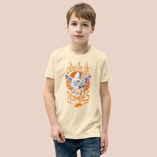 Garçcon sérieux portant un t-shirt jaune pâle illustré d'un monstre et inscrit Odeur de tombes. Vue du devant.