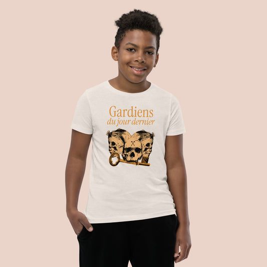 Garçon souriant portant un t-shirt de couleur naturel illustré de têtes de squelette et inscrit Gardiens du jour dernier. Vue du devant.