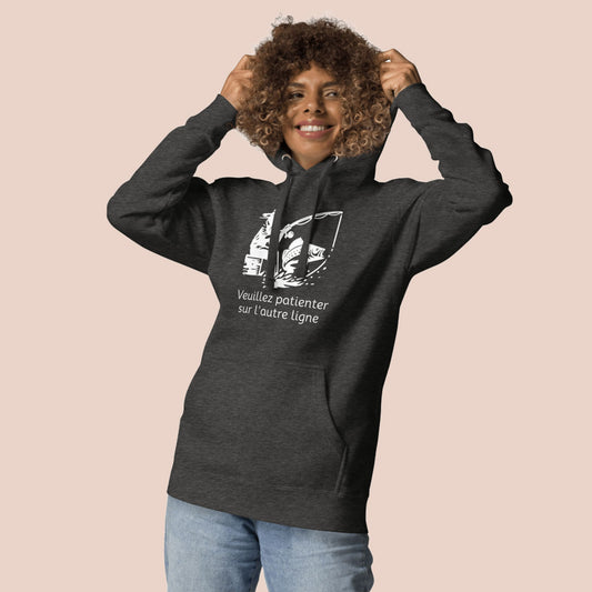 Femme portant un hoodie gris charbon avec motif pêcheur et texte « Veuillez patienter sur l'autre ligne » - Artic60